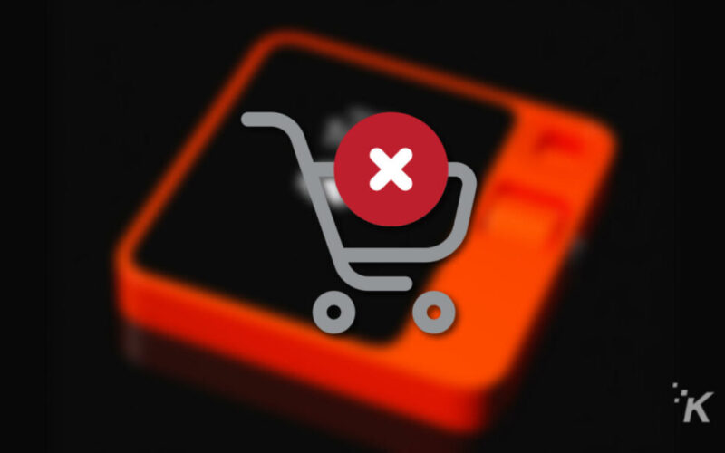 Red X over shopping cart on blurred rabbit r1 device in background