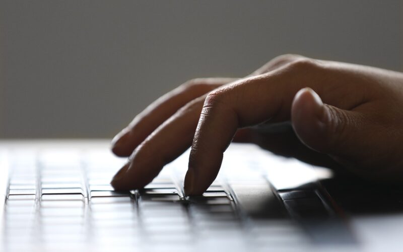 fingers typing on a black laptop keyboard