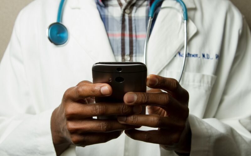 Doctor on a smartphone illustrating the AI Airlock scheme from the Medicines and Healthcare products Regulatory Agency (MHRA) in the UK that aims to accelerate the adoption of artificial intelligence technologies into the NHS healthcare system with a high emphasis on safety.